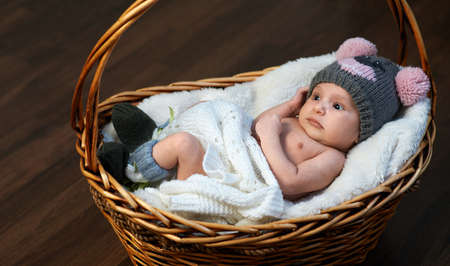 newborn baby in the cap in the basket on the floorの写真素材