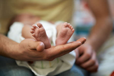 Dad holds in his hands a small baby footsの写真素材