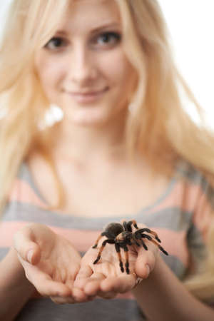 girl holding a large spider on her hands and smilingの写真素材