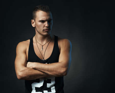 man on a black background with his arms crossed looking sidewaysの写真素材
