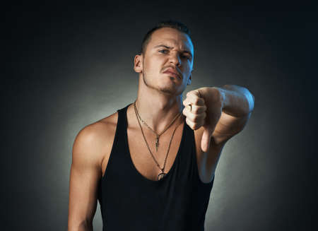 man showing thumbs down on a black backgroundの写真素材
