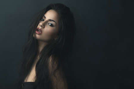 beautiful girl with tousled hair in the atmospheric darknessの写真素材