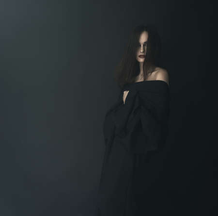 Scared woman in black in the fogの写真素材