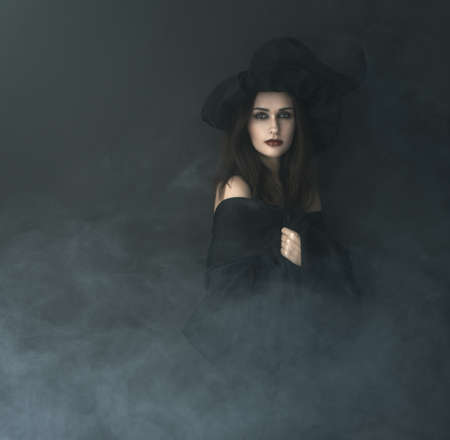 slender witch in a smoke on a black backgroundの写真素材