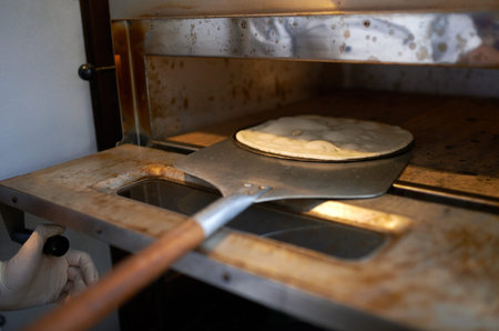 Cook on a shovel lozhit pizza dough in the ovenの写真素材