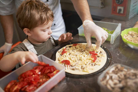 boy learning to cook pizza with the chefの写真素材