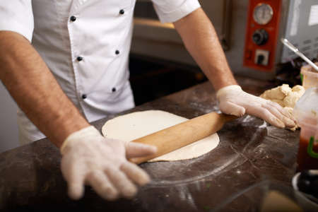 Chef rolls raw pizza doughの写真素材