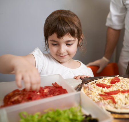 Girl puts tomatoes on the pizzaの写真素材