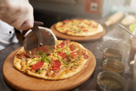 Chef cuts the pizza into slicesの写真素材