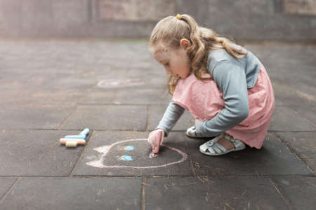 little girl draws a chalk on asphaltの写真素材