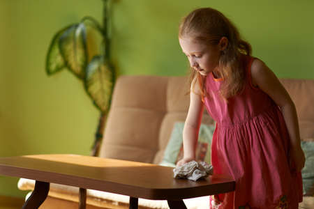 little girl cleans dust cloth on the tableの写真素材