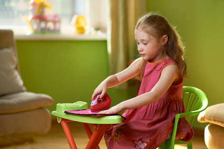 irons little girl sitting on a chair playingの写真素材