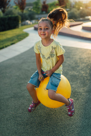 happy  girl is jumping on the yellow ball