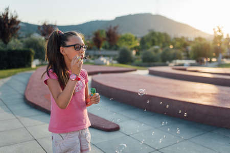 Beautiful girl is staying and blow bubbles on the groundの写真素材