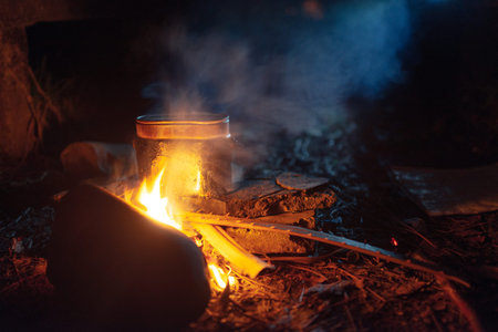 food is cooked in a pot over a campfire at nightの写真素材