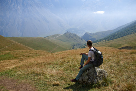 The man looking on the rock to the majestic mountais view