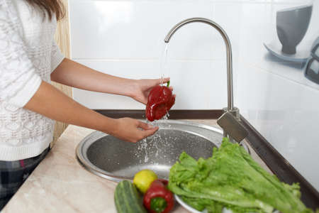 girl clean papper under water to prepare dinnerの写真素材