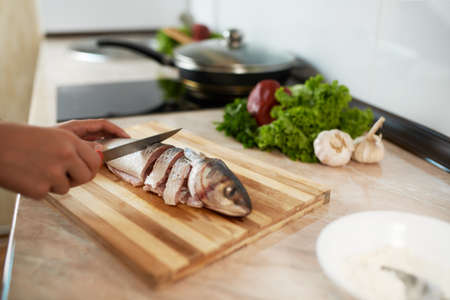 girl cut slice of  fish to cook tasty dishの写真素材