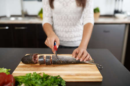 girl cut fish to cook tasty dinnerの写真素材