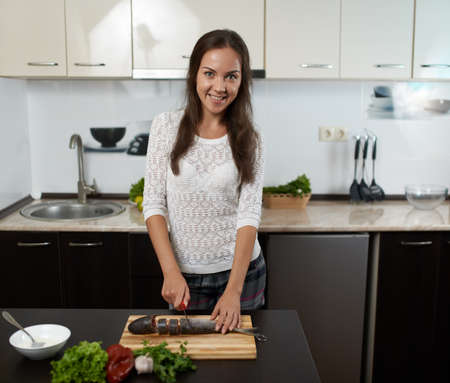 smiling girl prepare dinner in the kitchenの写真素材