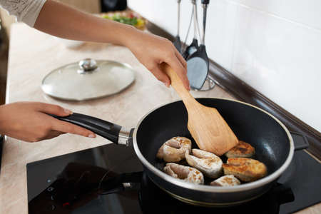 girl cooks fry fish in the kitchenの写真素材