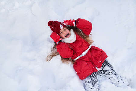 The girl fell into the snow and laughingの写真素材