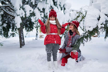 Mother and daughter walking in a snowy parkの写真素材