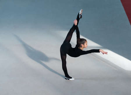 beautiful girl in a suit making a balance on one legの写真素材