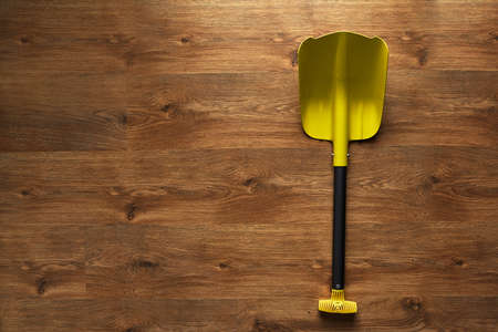Folding small yellow shovel lying on the wooden floorの写真素材