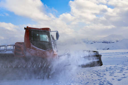snowcat rides to work in the evening at sunsetの写真素材