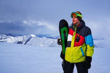 Snowboarder carries a board in the hands. Evening snowfall in the mountains.の写真素材