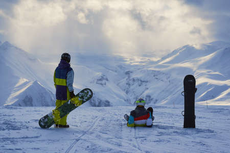 Snowboarders have a rest and look at the winter mountains landscape.の写真素材