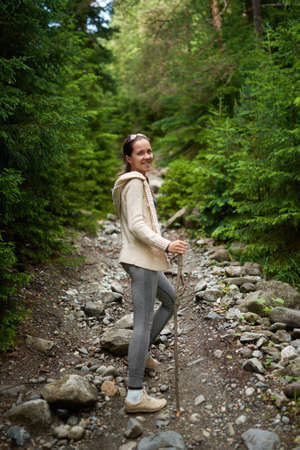 cheerful girl walking through a forest path, looking back smilingの写真素材