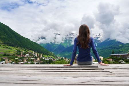 girl sitting on the roof of the house and looking into the distance on an ancient city Mestia in...