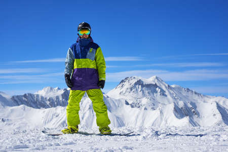 snowboarder standing on the top of a mountain on the background of a cliff top in winterの写真素材