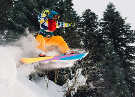 snowboarder with special equipment is jumping very high and freeriding from hill in the mountain forestの写真素材