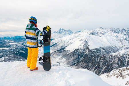 Snowboarder is standing with snowboard in the mountainの写真素材