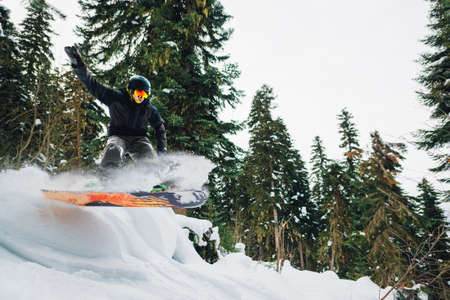 snowboarder with special equipment is riding fast, jumping, freeriding in the mountain forestの写真素材