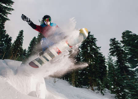 snowboarder with special equipment is jumping very high and freeriding from hill in the mountain forestの写真素材