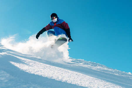 snowboarder is riding with snowboard from powder snow hill or mountain very fastの写真素材