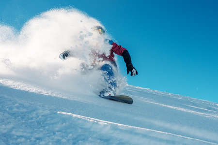 snowboarder is riding with snowboard from powder snow hill or mountain very fastの写真素材