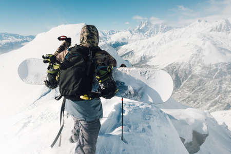 sportsman go with snowboard equipment on the snow hill and mountain rangeの写真素材