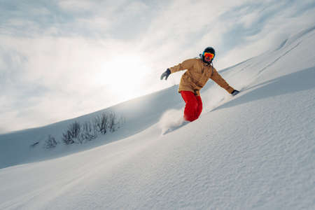 snowboarder is riding with snowboard from powder snow hillの写真素材