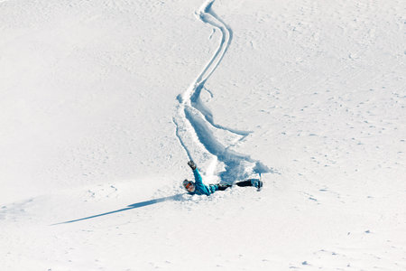 girl is riding with snowboard from powder snow hill and fall down