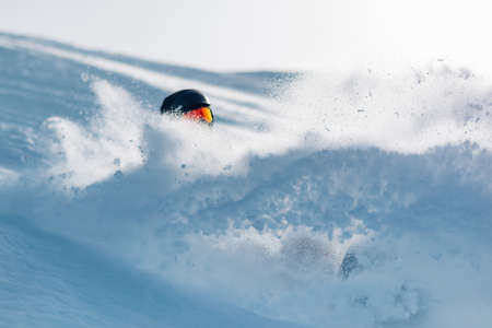snowboarder is riding with snowboard from powder snow hill or mountain very fastの写真素材