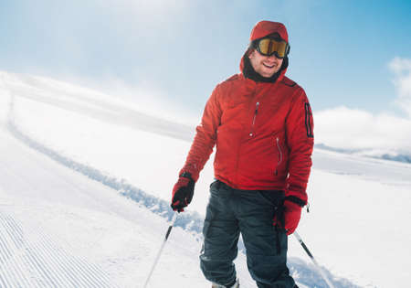 Happy man is staying on the snow in the mountain hill and smileの写真素材