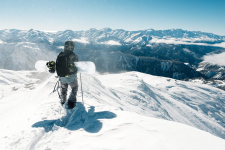 Snowboarder is standing with snowboard in the mountain