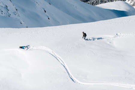 men is walkig under the mountain and help sportsman with snowboardの写真素材
