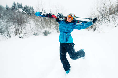 girl walk with ski equpment on the snow hill with green forest in ski touringの写真素材
