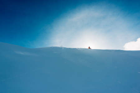 snowboarder is sitting on the snow hill with snowboard and watchingの写真素材